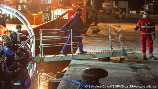A migrant gets off the Mare Jo<em></em>nio ship, as Red Cross staff is seen welcoming him | Photo: Salvatore Cavalli / SOPA Images/Sipa USA